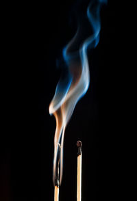 Close-up of smoking matchstick on black background