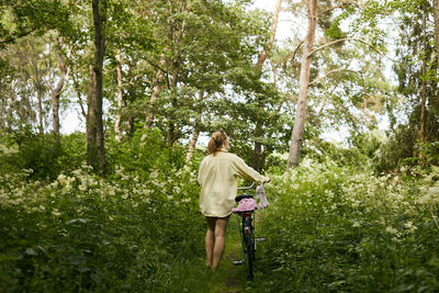 Woman walking with bicycle in forest
