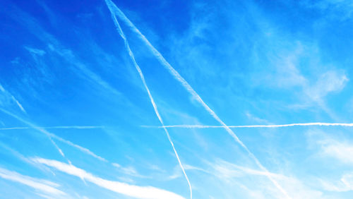 Low angle view of vapor trails against blue sky