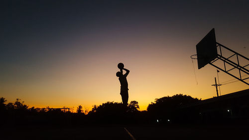 Silhouette man playing soccer against sky during sunset