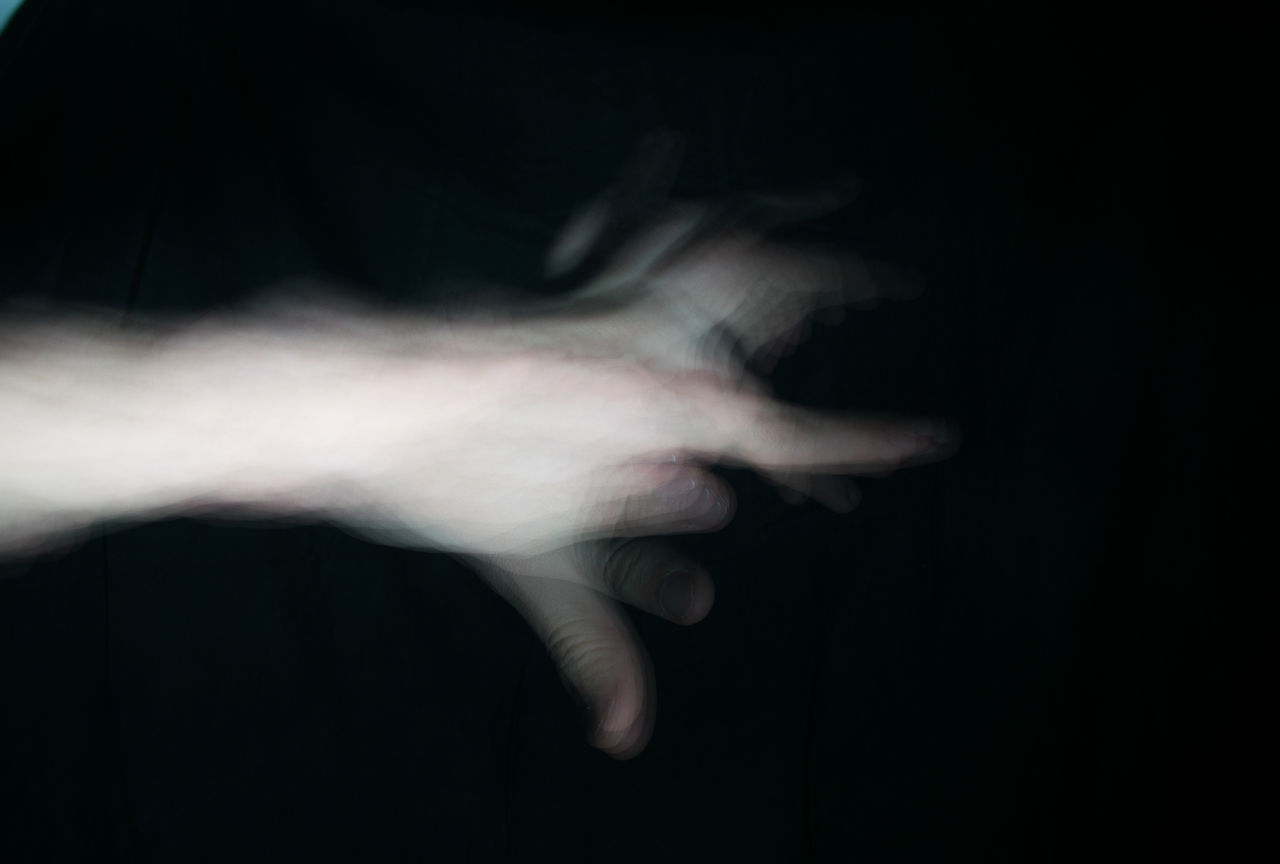 CLOSE-UP OF CROPPED HANDS OVER BLACK BACKGROUND