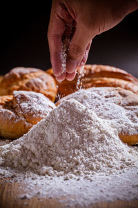 Cropped hand of woman holding flour while making croissant