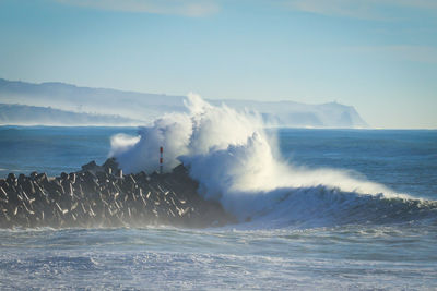 Waves splashing on sea against sky