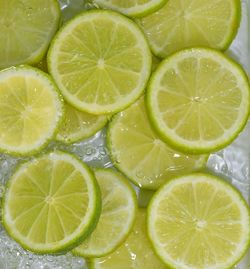 Slices of limes fruit in water on white background. limes close-up in liquid with bubbles. 