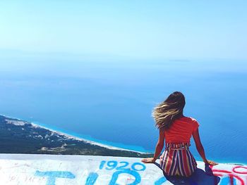 Rear view of woman looking at sea against blue sky