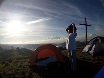 Woman standing in tent on mountain against sky