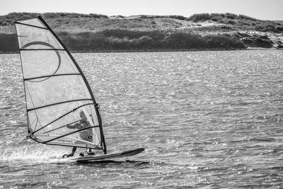 Person windsurfing on water against sky
