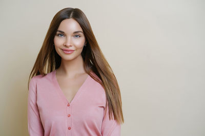 Portrait of young woman standing against white background