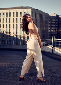 Side view of young woman standing against buildings