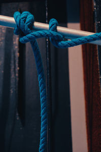Close-up of blue rope tied on metal rod