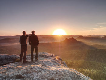 Hikers and friends stay on cliff within dreamy daybreak and thinking. dreamy fogy landscape mist