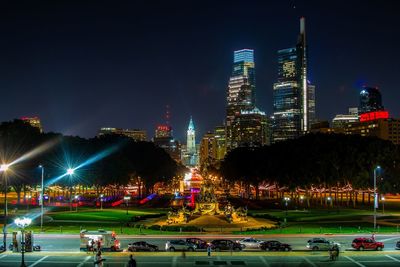 Illuminated modern buildings in city against sky at night