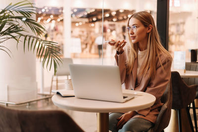 A young millennial student records a voice message and studies online using a laptop and smartphone