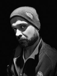 Portrait of young man against black background