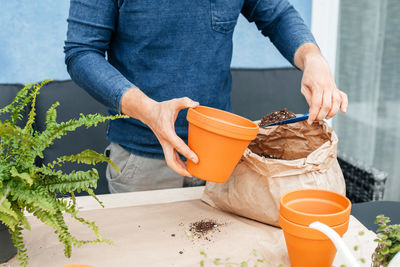 The hands of a male gardener who transplants plants, pours gruet into a flower pot. 