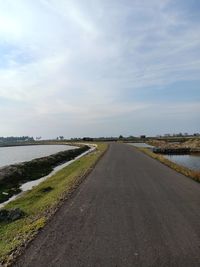 Road amidst field against sky