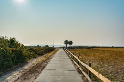 Road amidst field against clear sky