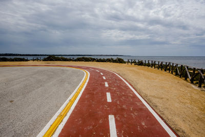 Empty road by sea against sky