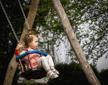 Low angle view of boy swinging at playground