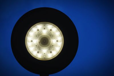 Low angle view of illuminated lamp against clear blue sky