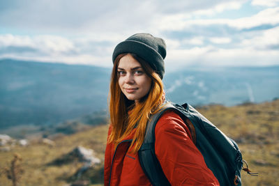 Portrait of young woman standing against sky