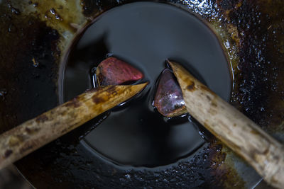 Close-up of tjanting needles in utensil with liquid wax