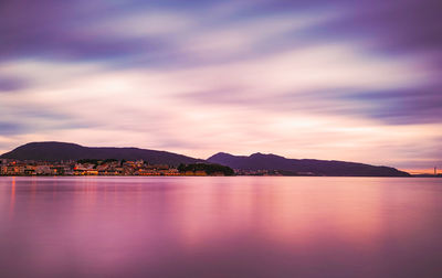 Scenic view of lake against dramatic sky during sunset