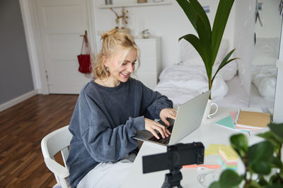 Side view of young woman using digital tablet while sitting at home