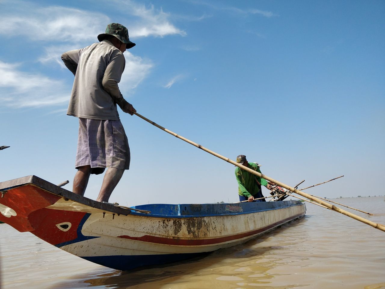 nautical vessel, transportation, mode of transport, water, real people, men, day, boat, full length, outdoors, casual clothing, occupation, fisherman, sky, nature, standing, beauty in nature, moored, lifestyles, scenics, working, longtail boat, one person, people