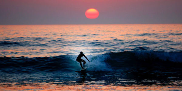 Silhouette man surfing in the sea