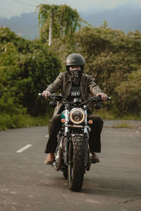 Side view of man riding motor scooter on road