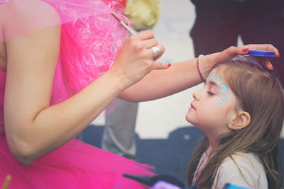 Midsection of woman applying face paint to girl