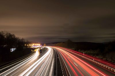 Light trails on road against sky at night