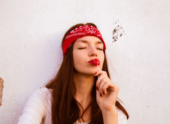 Portrait of beautiful young woman against wall