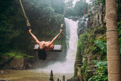 Young woman on swing against waterfall