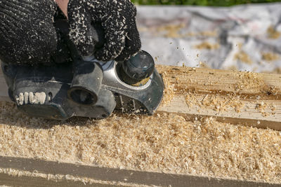 A view of electric plane, a tool in the hands of a person who is planing wooden material