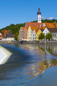 Buildings at waterfront against blue sky