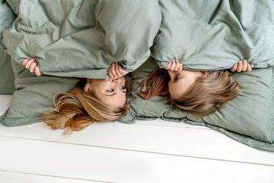 High angle view of siblings lying on bed