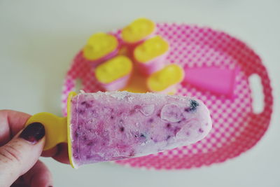 Close-up of woman hand holding flavored ice on table