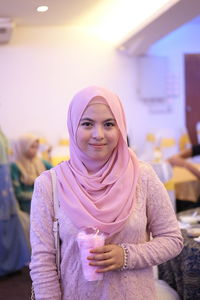 Portrait of smiling young woman standing against wall