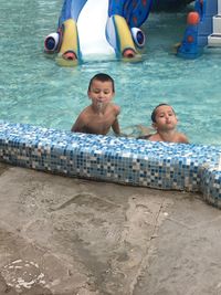 Portrait of happy boy sitting in swimming pool