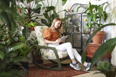 Young woman sitting on chair against plants