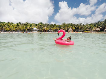 Young woman relaxing on pool raft in sea during vacation