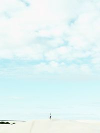 Distant view of woman standing on desert against sky