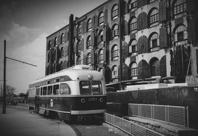 Train by buildings in city against sky