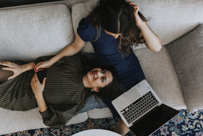 High angle view of woman using mobile phone on sofa