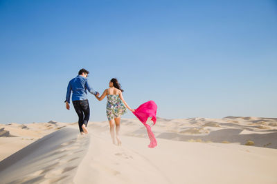 Rear view of people walking on beach