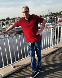 Portrait of man standing on footbridge against sky