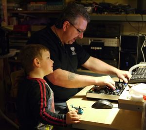 Man mixing records with son on desk at home