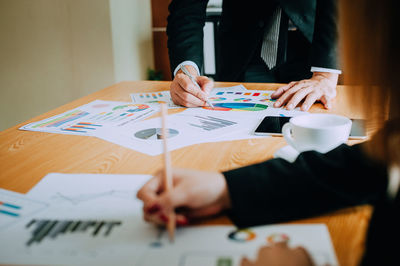 Midsection of man holding paper on table